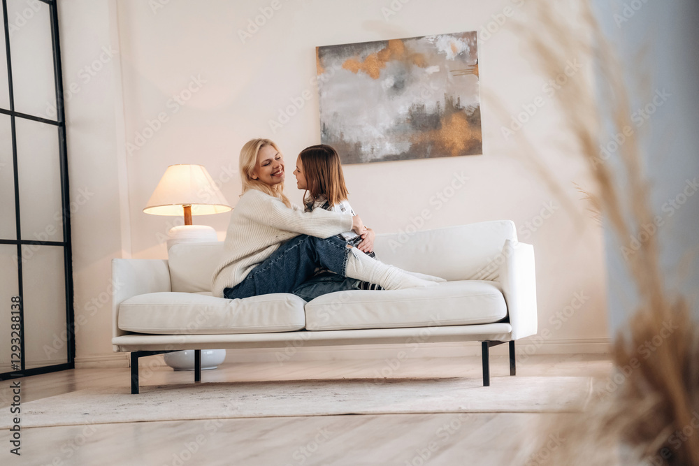 Closeness, sitting on the sofa. Mother and daughter are together in domestic room Closeness, sitting on the sofa. Mother and daughter are together in domestic room