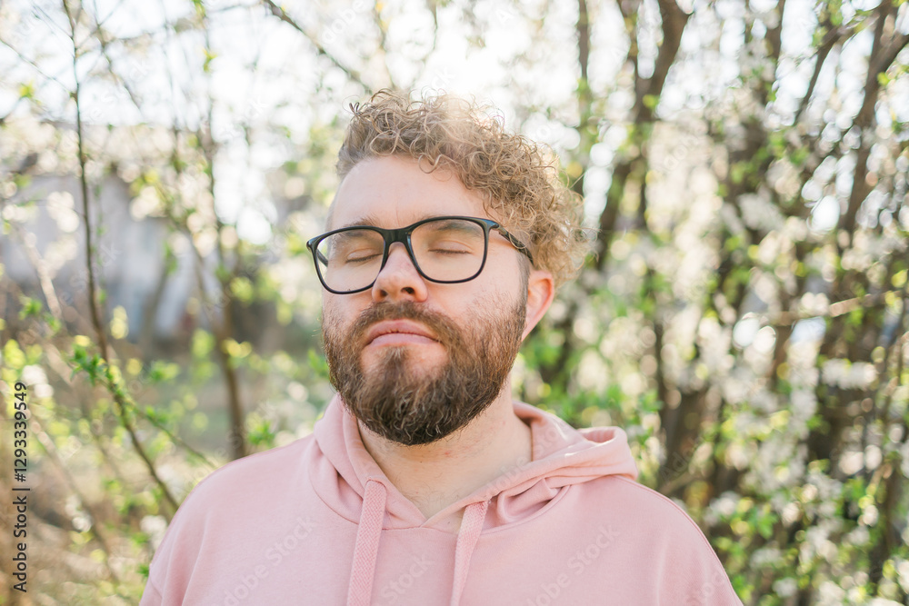 Man with beard and mustache near sakura flowers or blooming spring tree. Soft and gentle concept. Bearded man with stylish haircut with flowers on background, close up. Hipster near branch of bloom Man with beard and mustache near sakura flowers or blooming spring tree. Soft and gentle concept. Bearded man with stylish haircut with flowers on background, close up. Hipster near branch of bloom