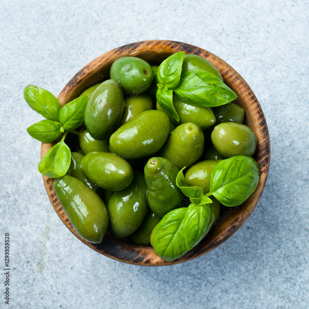 A wooden bowl with marinated olives. on a gray concrete background. Close up. A wooden bowl with marinated olives. on a gray concrete background. Close up.