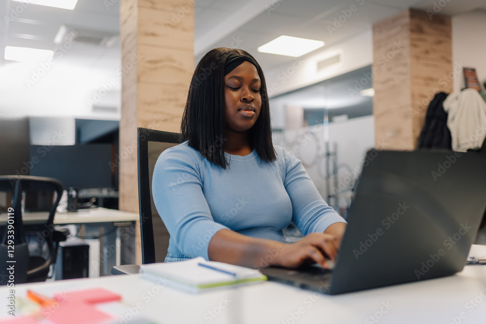 Fototapeta premium Focused female entrepreneur working on laptop in modern office