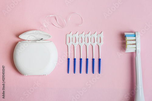 Oral Care: electric toothbrush, dental floss, brush for cleaning interdental spaces on pink background. Concept: dental services and care, oral hygiene photo