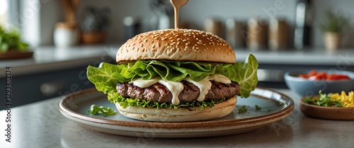 Delicious Grilled Beef Burger with Fresh Lettuce and Creamy Mayonnaise on a Ceramic Plate in Bright Kitchen Setting with Copyspace