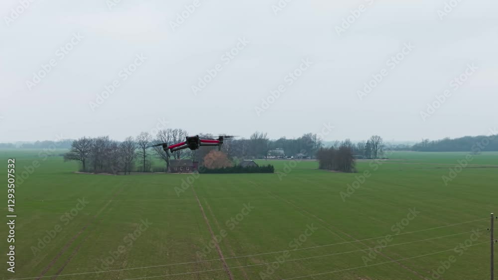 A quadcopter drone in flight over a green field, maintaining altitude in an open rural setting A quadcopter drone in flight over a green field, maintaining altitude in an open rural setting
