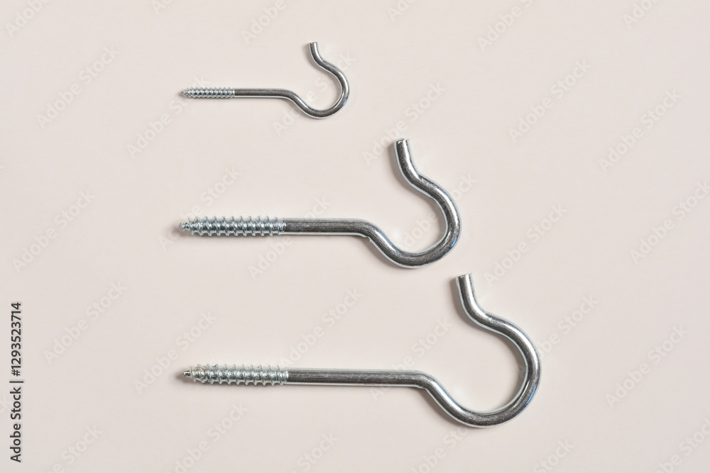 A top-down shot of three different sizes of zinc-plated steel screw hooks arranged in a row A top-down shot of three different sizes of zinc-plated steel screw hooks arranged in a row