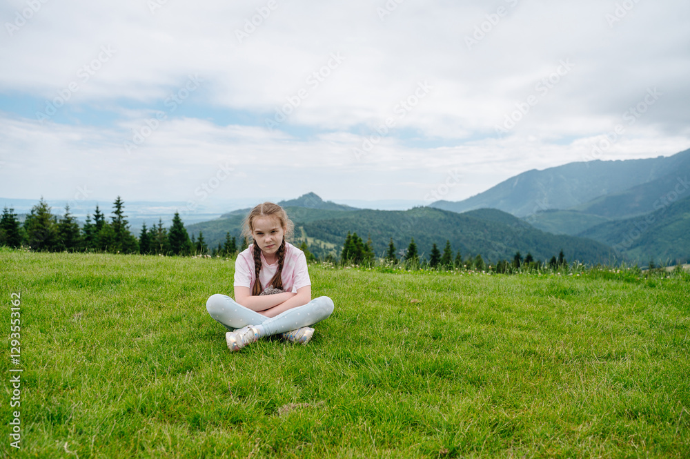 Young girl sitting on grass with Bachledka mountains in backdrop Young girl sitting on grass with Bachledka mountains in backdrop