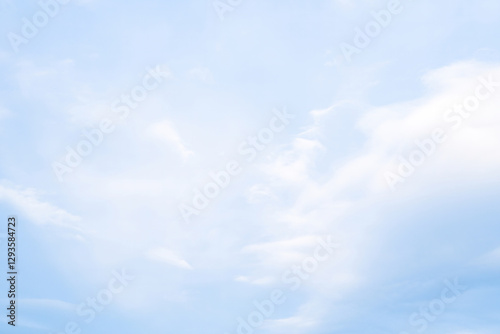 Soft clouds drift across a serene blue sky in the early afternoon light