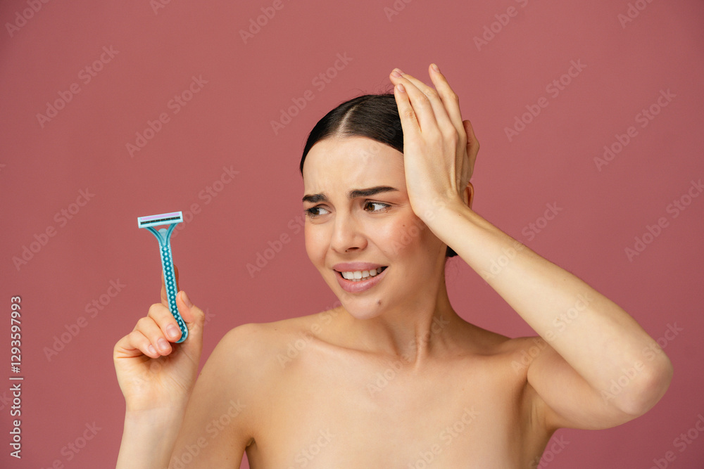 Individual is visibly perplexed while holding a razor, set against a plain pink backdrop. Individual is visibly perplexed while holding a razor, set against a plain pink backdrop.
