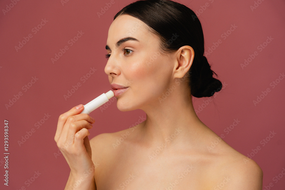 Close-up portrait of girl moisturizing lips with lip balm against pink backdrop, featuring healthy glowing skin, natural beauty, minimalistic self-care routine. Ideal for skincare and beauty concepts. Close-up portrait of girl moisturizing lips with lip balm against pink backdrop, featuring healthy glowing skin, natural beauty, minimalistic self-care routine. Ideal for skincare and beauty concepts.
