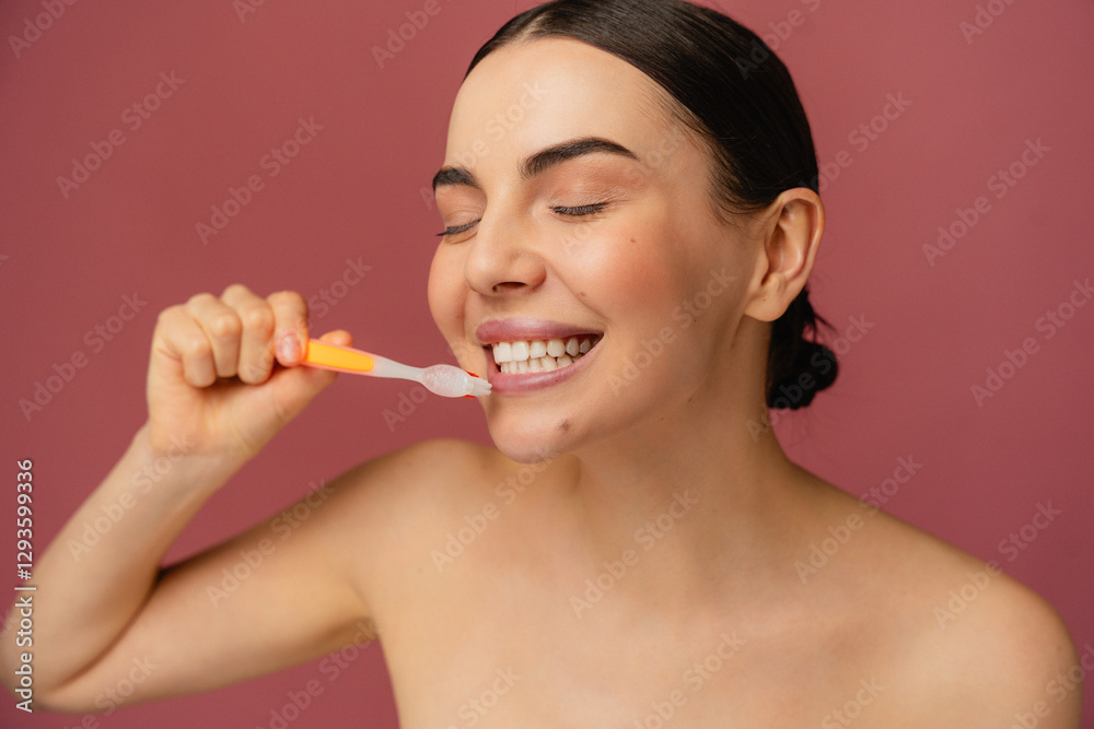 Person brushing teeth with enthusiasm, promoting health and hygiene, set against a vibrant pink background. Person brushing teeth with enthusiasm, promoting health and hygiene, set against a vibrant pink background.