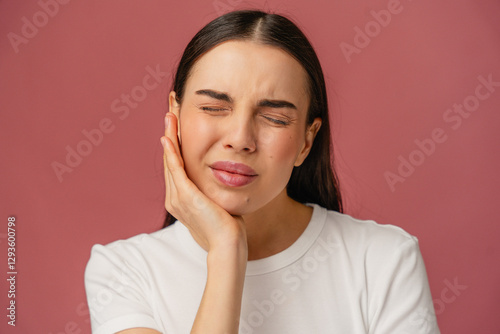 Individual with a distressed expression touches the cheek, indicating discomfort or toothache.