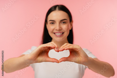 Bright and cheerful individual expressing love and positivity through a heart gesture with hands. The soft pastel background enhances the warm and loving feeling conveyed by the composition.