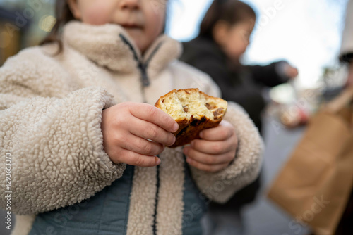 Close-up of a child in a fluffy coat holding a half-eaten piece of bread, Netherlands photo