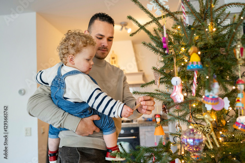 Father holding his young child while decorating a Christmas tree together, Netherlands photo