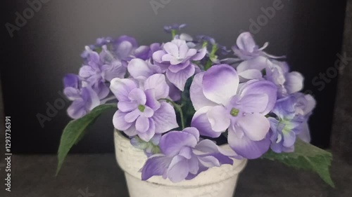 Beautiful light purple flowers are in a white vase on a slightly dark background