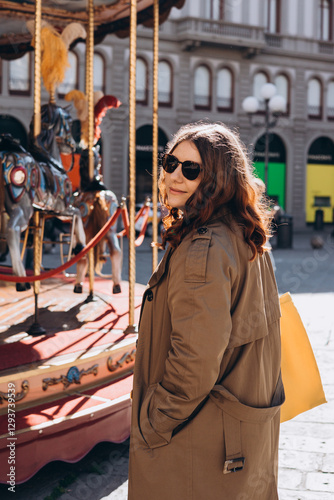 Cheerful young pretty woman in sunglasses with brown hair walking in park of attractions, wearing casual clothes