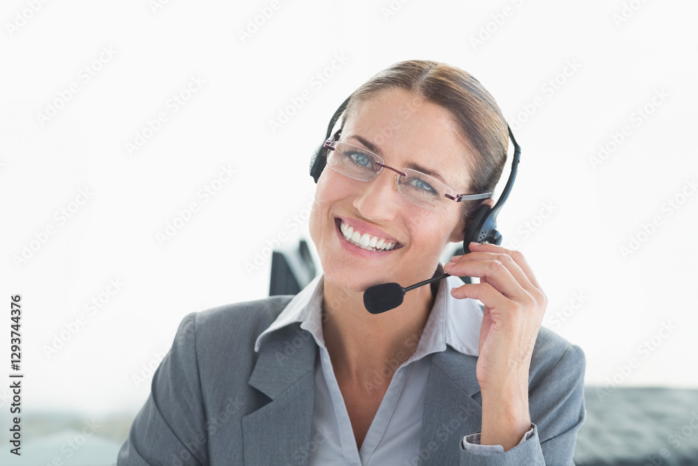 In office, businesswoman using headset providing customer support, smiling warmly In office, businesswoman using headset providing customer support, smiling warmly