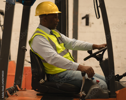 Warehouse worker driving forklift, wearing safety vest and helmet, focused on task photo