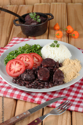 Comida tipica brasileira:  feijoada com acompanhamentos, servida no prato e na tigela
