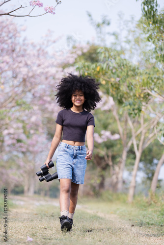 Wallpaper Mural A teenager with voluminous curly hair stands on a dirt path surrounded by blooming trees, holding binoculars.  Torontodigital.ca