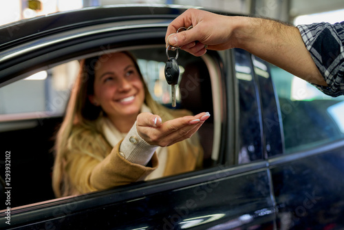 Bild auf Leinwand Smiling woman joyfully receiving car keys from a mechanic after completing maint