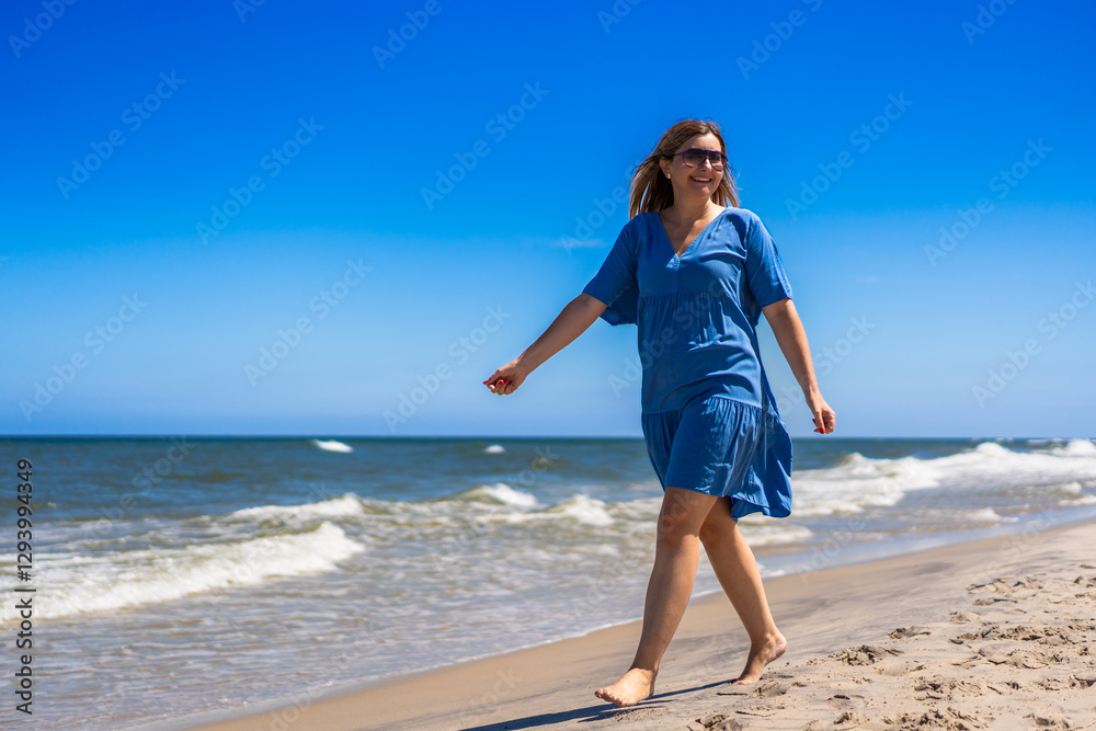 Portrait of beautiful middle-aged woman enjoying walk on sandy beach on sunny summer day Portrait of beautiful middle-aged woman enjoying walk on sandy beach on sunny summer day