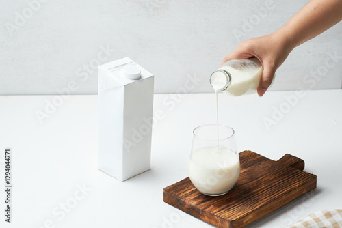 Pouring Fresh Milk From a Bottle Into a Glass on a Wooden Cutting Board photo