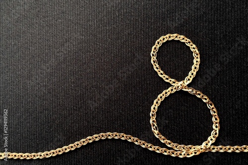 Stylish dark card for Women's Day March 8, figure eight made of gold chain on a textured black background. Celebrating International Women's Day. Concept March 8.