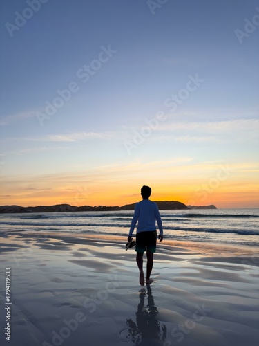 Man walking on the beach at sunset