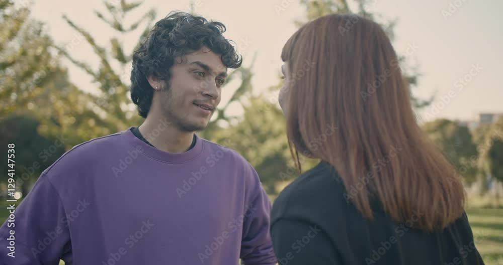 A young man and woman have a serious discussion in a park. They are both dressed casually. A young man and woman have a serious discussion in a park. They are both dressed casually.