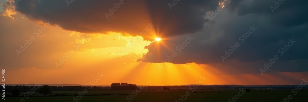 Fototapeta premium Golden rays pierce dark clouds, illuminating landscape, weather, break in clouds, heaven