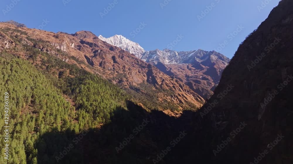 Dramatic sunlight streaming over snow capped Himalayan peak, creating intricate shadows across verdant valley landscapes near Monjo village in Nepal Dramatic sunlight streaming over snow capped Himalayan peak, creating intricate shadows across verdant valley landscapes near Monjo village in Nepal