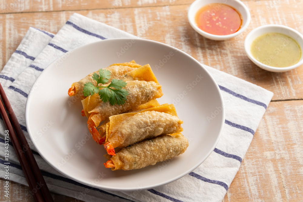 Deep Fried Crispy Wonton wrapped with shrimp and minced pork in white plate.Thai appetizer food with Sweet Chili Sauce and seafood sauce. Deep Fried Crispy Wonton wrapped with shrimp and minced pork in white plate.Thai appetizer food with Sweet Chili Sauce and seafood sauce.