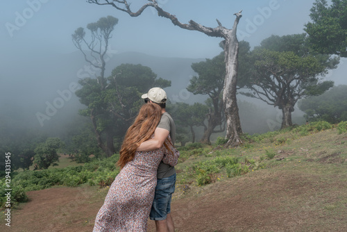 Couple looking to the foggy fanal forest.