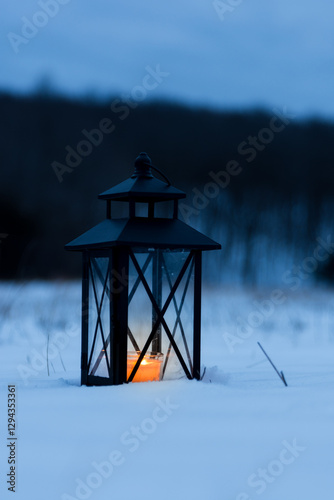 a lanten with a candle in the snow photo