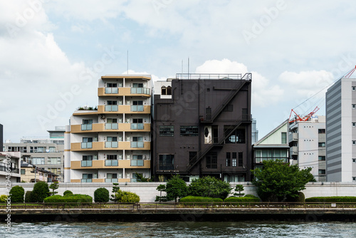 Photography An array of buildings lines the riverbank, showcasing diverse modern architecture under a cloudy sky