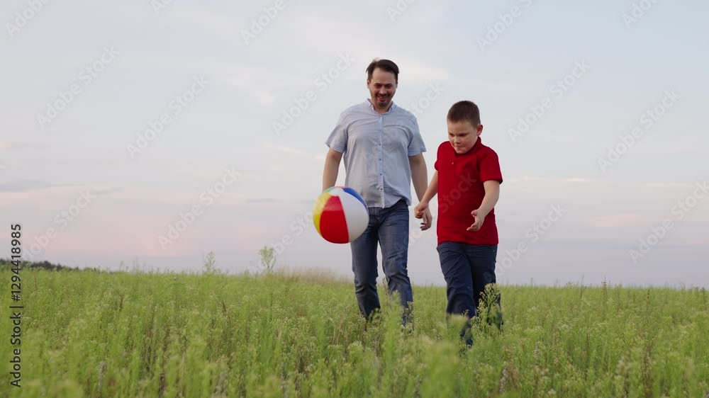 The boy is playing with a colorful ball, his father is happily watching him, they are enjoying their time together, the child is excited to kick the ball, the father follows him with a smile, they are The boy is playing with a colorful ball, his father is happily watching him, they are enjoying their time together, the child is excited to kick the ball, the father follows him with a smile, they are