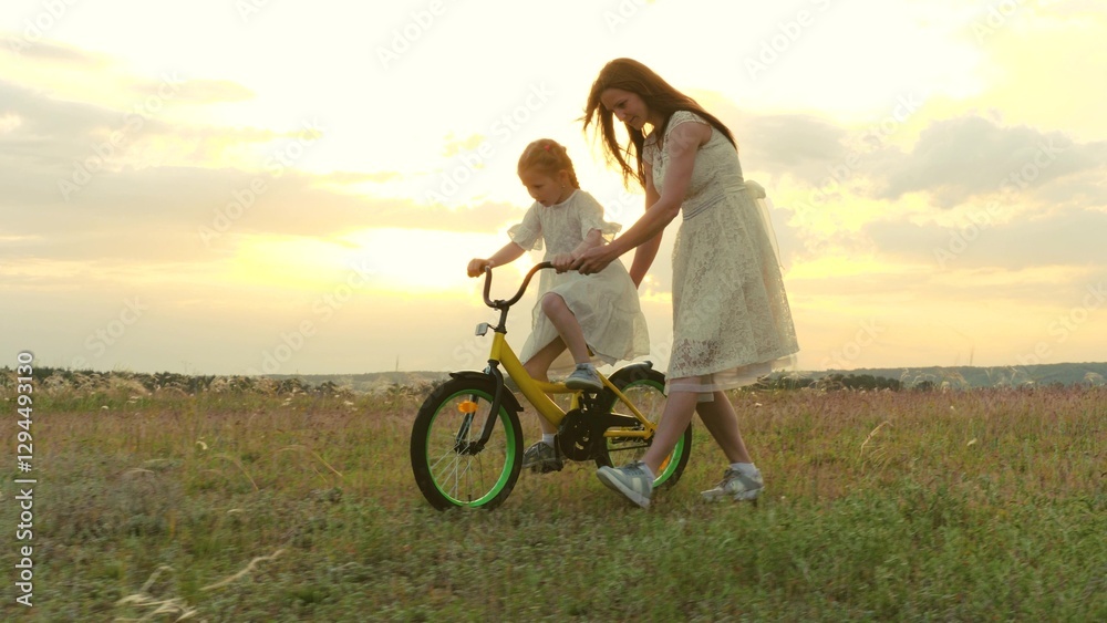 Obraz premium happy family. child girl learning ride bike. mom daughter kid spend time bike park. concept children dream. mother child play outdoors. little girl pedals steers bicycle park. young mother with kid