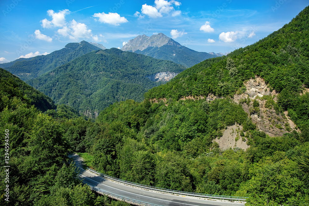 Majestic mountain landscape views along winding road in a sunny afternoon.