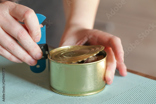 Womans hands open tin can with an can opener. Canned food and special knife photo