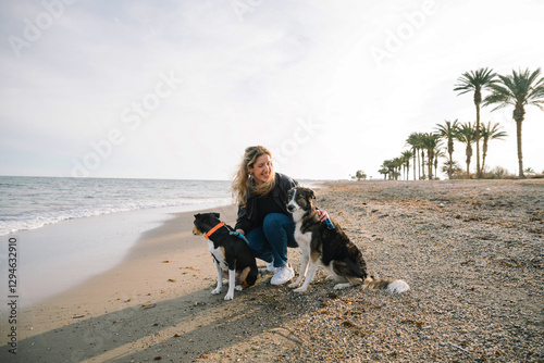 Photography Woman walking with two dogs on the beach at sunset