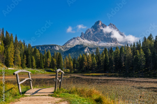 Obraz na płótnie Tre Cime di Lavaredo during sunrise with warm golden light with small bridge and lake in the foreground w salonie
