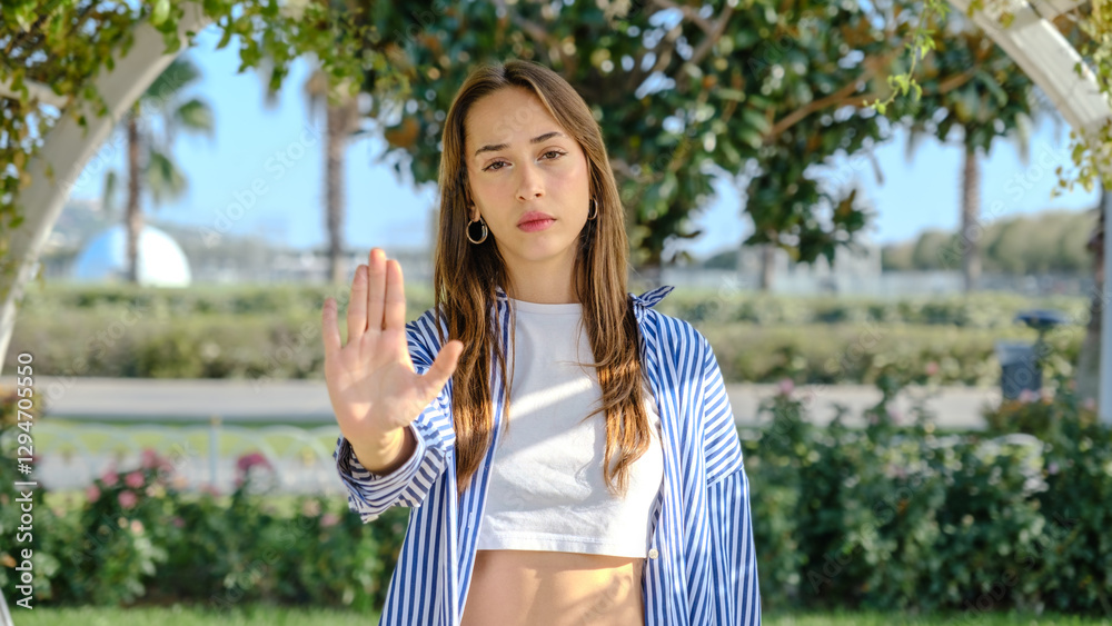 A young businesswoman in a tree-filled park on a spring day, looking at the camera while making a A young businesswoman in a tree-filled park on a spring day, looking at the camera while making a