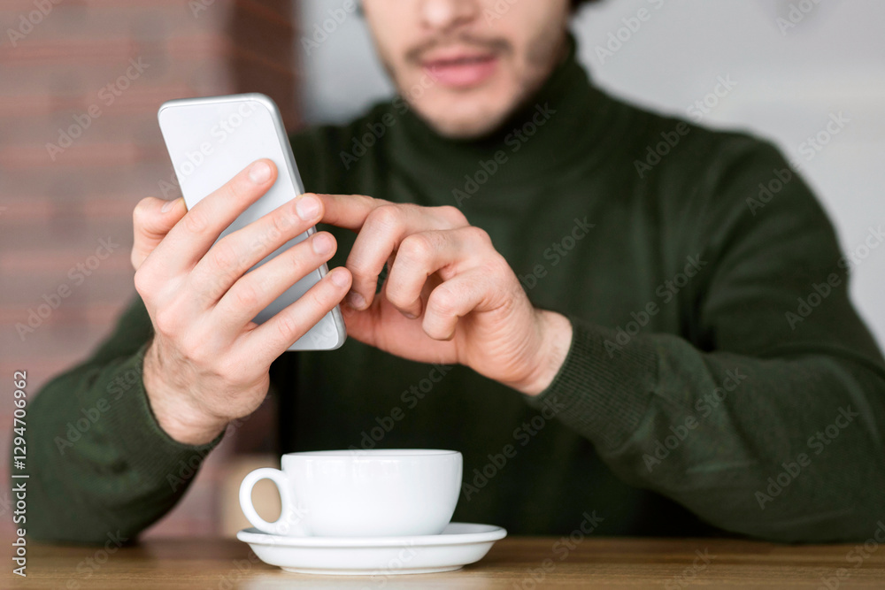 Cropped of guy using modern smartphone and cup of cofee, cafe interior Cropped of guy using modern smartphone and cup of cofee, cafe interior