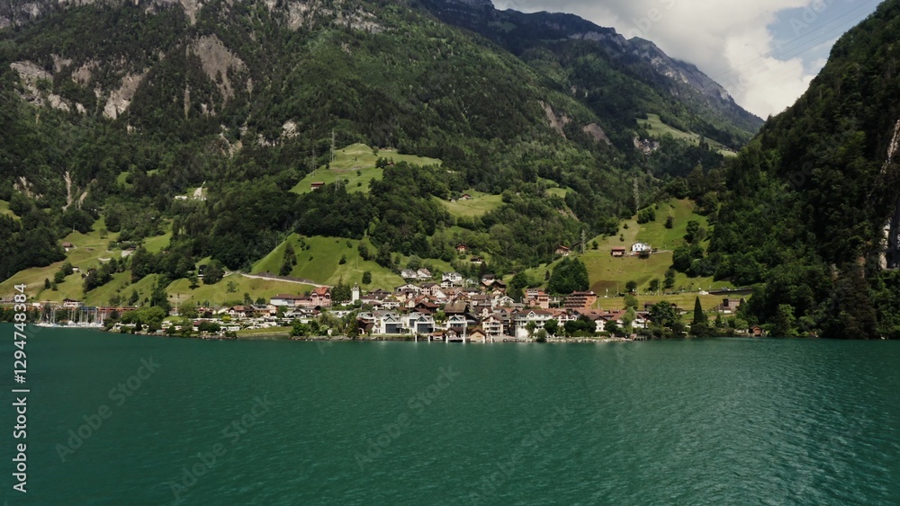 Scenic drone video, beautiful view of a modern village with a cottage development in a lowland between the Alpine mountains on the lake shore Scenic drone video, beautiful view of a modern village with a cottage development in a lowland between the Alpine mountains on the lake shore