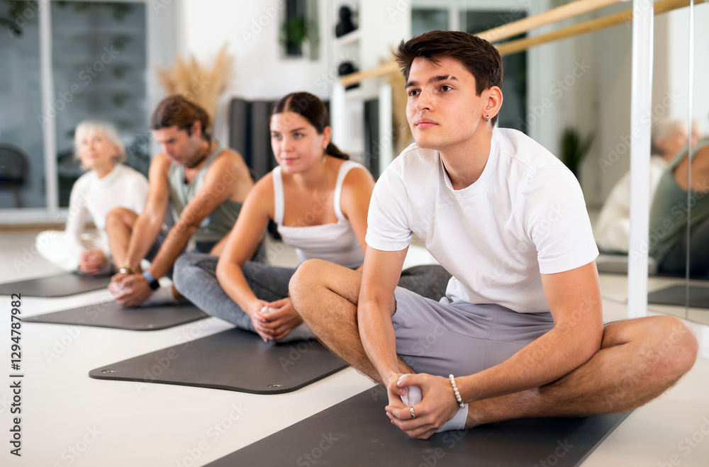 Slim young man practicing pilates exercises in training area during pilates classes Slim young man practicing pilates exercises in training area during pilates classes