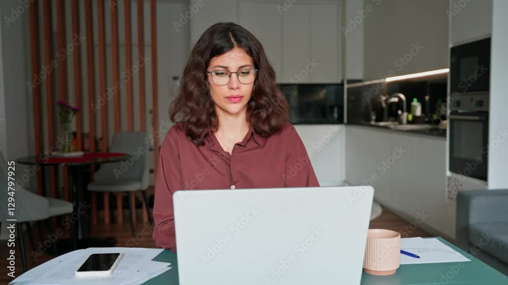 Focused financial or IT specialist business woman working on laptop pc at home, doing work remotely. Middle eastern or latin businesswoman using computer application for online remote work. Copy space