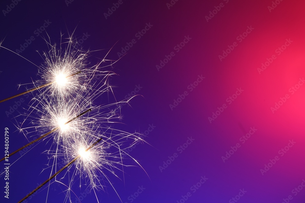 Naklejka premium Bright burning sparklers on color gradient background, closeup. Space for text