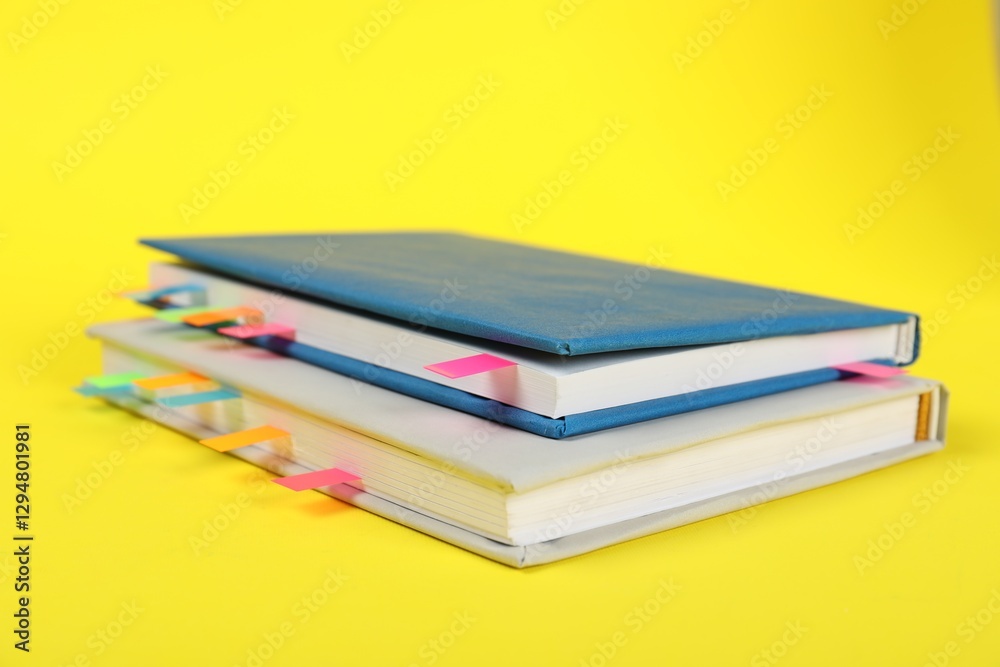 Books with colorful tabs on yellow background, closeup Books with colorful tabs on yellow background, closeup