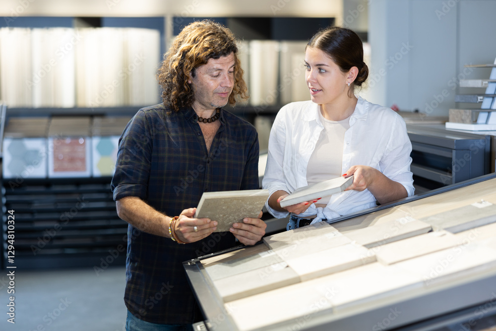 Obraz premium In construction mall,wife with husband inspects drawing of decorative slabs for interior decoration. Turnkey repairs, finishing materials, apartment renovation