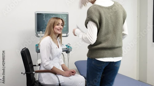 An ultrasound specialist consults a patient about the procedure in a modern office near the ultrasound machine. The concept of advanced technology and a professional approach in medical diagnostics.